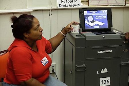 An election worker sits next to an electronic voting machine at a polling place in Washington, DC during the US presidential election on November 8, 2016.